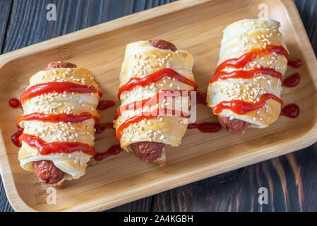 Sausage rolls on the wooden tray: top view