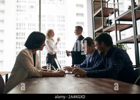attractive two guys consulting female client at workplace, two colleagues discussing a problem in the background of the photo Stock Photo