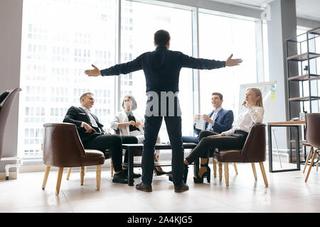 emotional conversation, back view full length photo.man asking his co-workers to cingratulate him with promotion, panorama window in the background of Stock Photo