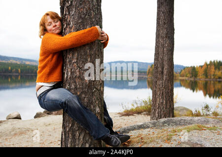 Woman hugging a tree - tree hugger/tree huggers Stock Photo
