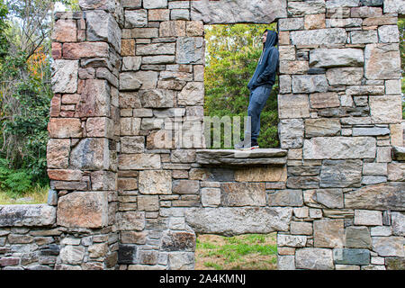 young man outdoors standing in window of abandoned building Stock Photo