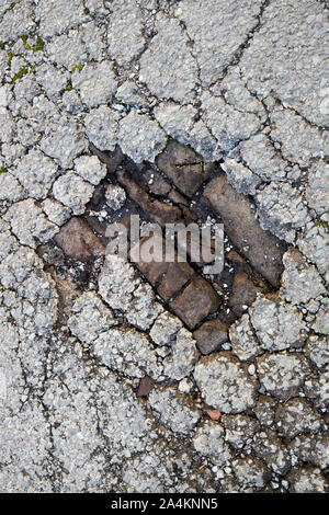 broken tarmac showing old cobblestoned street underneath hidden in georgian quarter Liverpool England UK Stock Photo