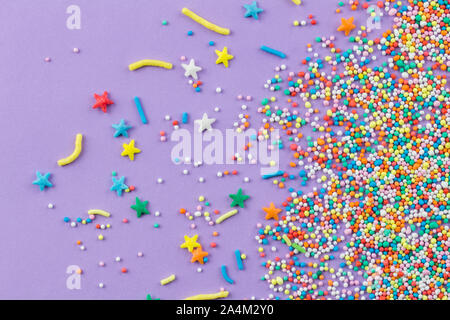 Sprinkles on purple background - Cake topping sprinkles sprayed on lilac background - top view Stock Photo