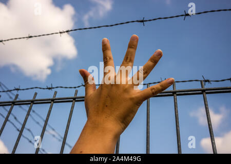 Refugee men hand and fence Stock Photo