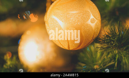 Closeup toned image of two golden balls with glitters hanging on Christmas tree Stock Photo