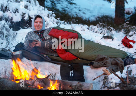 Woman resting in sleeping bag in the forest Nordmarka, Norway Stock Photo