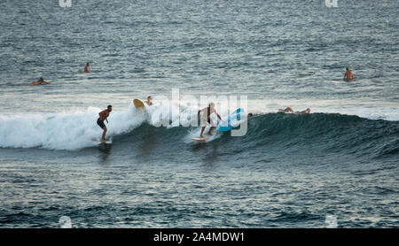 Two surfers riding a wave at Canggu beach in Bali, Indonesia Stock Photo