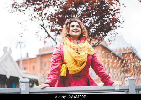 Beautiful cheerful curly red-haired woman against the background of holiday town Stock Photo