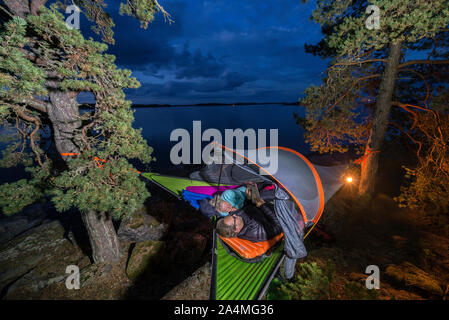 Man and woman sleeping in tent hanging on tree Stock Photo