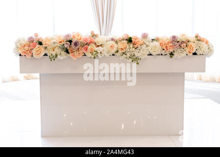 The groom and bride table near large bright windows and decorated with beautiful natural flowers Stock Photo