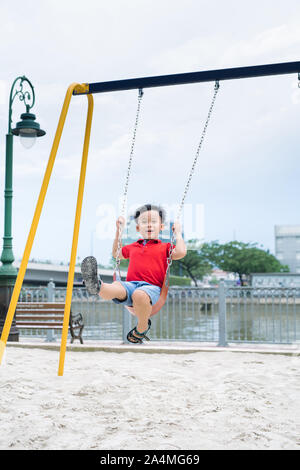 Adorable little boy having fun on a swing outdoor Stock Photo