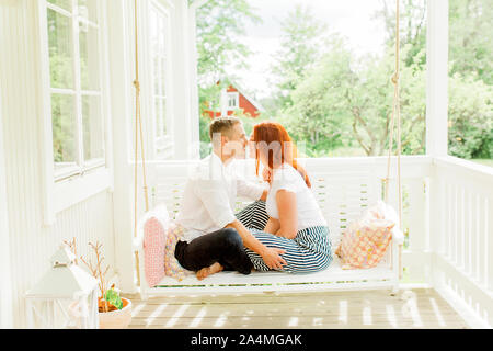 Couple sitting on swing in terrace Stock Photo