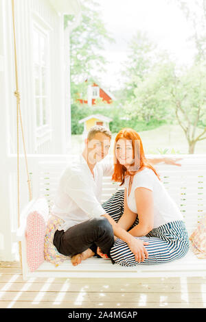 Portrait of couple sitting on swing in terrace Stock Photo