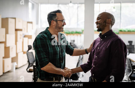 Two businessmen shaking hands smiling showing relief and joy. In congratulation Stock Photo