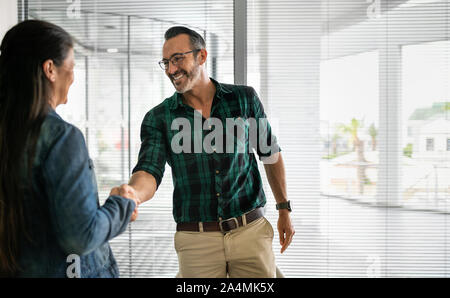 Handsome businessman shaking hands with fellow colleague and businesswoman with copy space Stock Photo
