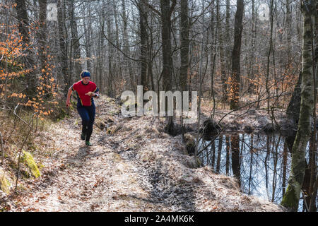 Woman running through forest Stock Photo