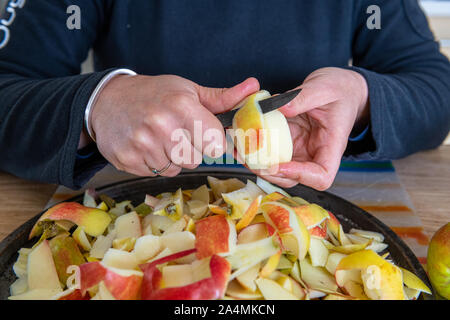 Hands peeling a cooking apple on a wooden board Stock Photo