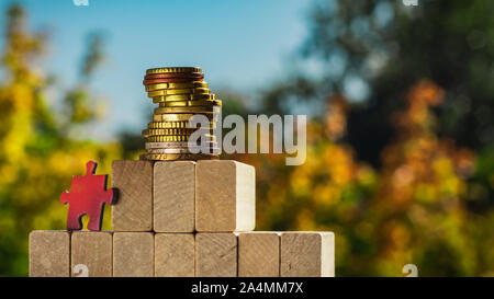 Puzzle climbs to the top of the pyramid made of wooden blocks. The concept of achieving business goals and reaching new levels of promotion. Stock Photo