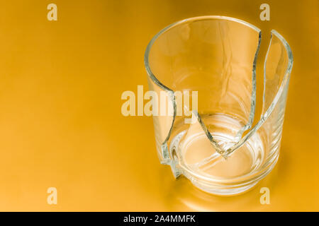 Broken glass dish on golden isolated background. Part of home decoration that was damaged during washing. Stock Photo