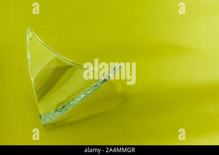 Broken glass dish on green lemon background. Part of home decoration that was damaged during washing. Stock Photo