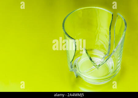 Broken glass dish on green lemon background. Part of home decoration that was damaged during washing. Stock Photo