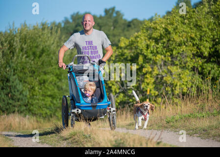 Father jogging with child in pram Stock Photo