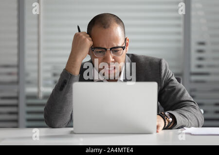 Unhappy African American businessman looking at laptop screen Stock Photo