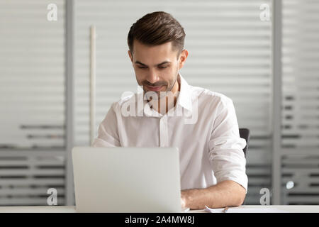 Focused businessman using laptop, busy employee working on project Stock Photo