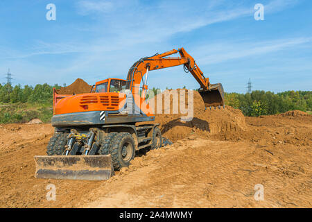 The modern excavator performs excavation work on the construction site. Stock Photo