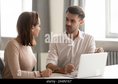 Serious businessman mentor teaching new female employee, using laptop Stock Photo