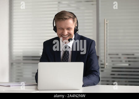 Happy smiling businessman in headset using laptop, working online Stock Photo