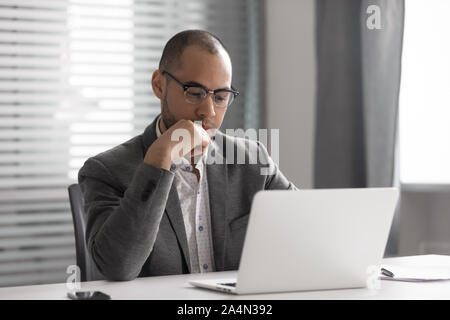 Thoughtful African American businessman using laptop, pondering project Stock Photo