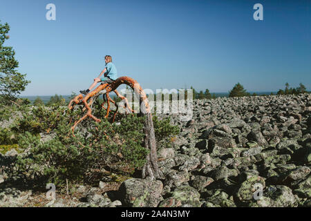 Boy sitting on bended tree Stock Photo