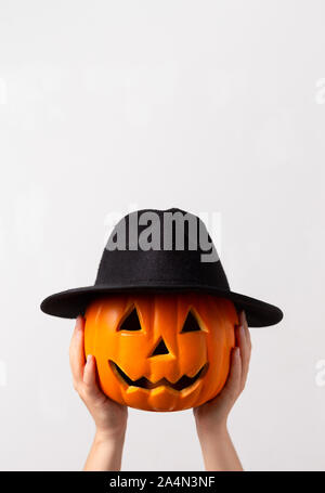 Creative halloween pumpkin in black hat preparing for party Stock Photo