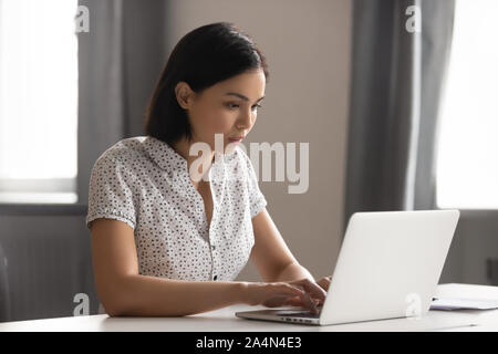 Serious focused Asian businesswoman employee intern using laptop Stock Photo