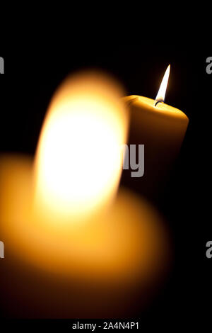 Two burning yellow candles on black background Stock Photo