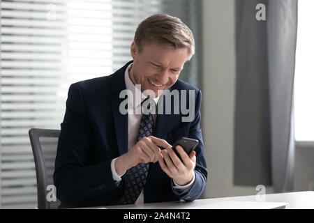 Smiling businessman using phone apps, having fun, good news Stock Photo