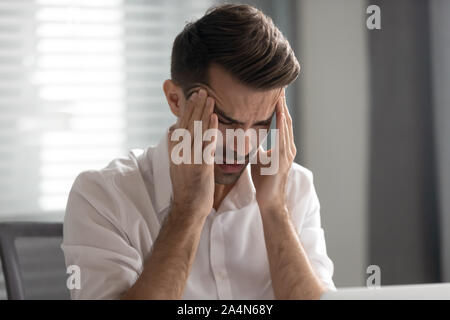 Unhappy businessman massaging temples, suffering from strong headache Stock Photo