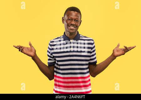 Nice to meet you. Young african-american man isolated on yellow studio background, facial expression. Beautiful male half-lenght portrait. Concept of human emotions, facial expression. Looking friendly. Stock Photo