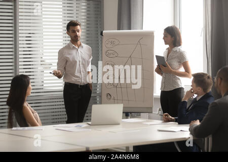 Asian businesswoman and Caucasian businessman making flip chart presentation Stock Photo