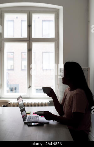 Woman having coffee in front of laptop Stock Photo