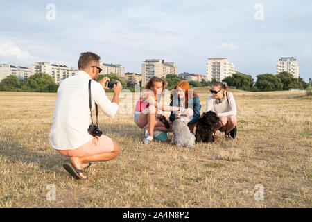 Father photographing his family playing with dogs Stock Photo