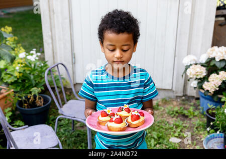 Boy holding plate with cupcakes Stock Photo