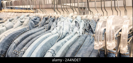 Male mens denim jeans shirts sorted on clothes hangers on a shop wardrobe closet Stock Photo