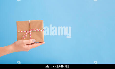 Gift box in cardboard on woman hand, blue Stock Photo