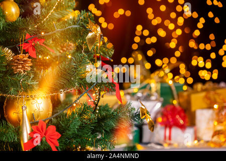 Stack of packed gift boxes under Christmas tree against particles lights. Lots of Christmas gifts under the tree. Selective focus on the yellow globe! Stock Photo