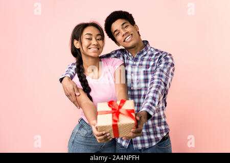 Happy young couple stretching present box to camera Stock Photo