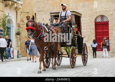 Tourists ride on a Horse and carriage tour of the historic city of Mdina on the island of Malta Stock Photo