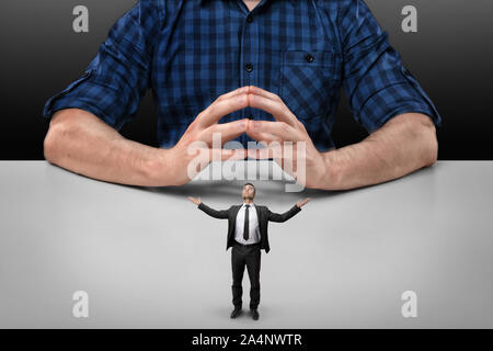 Businessman stands with raised hands in front of cropped portrait big man sitting Stock Photo