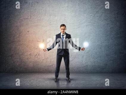 Front view of a businessman standing and holding glowing light bulbs in both hands Stock Photo